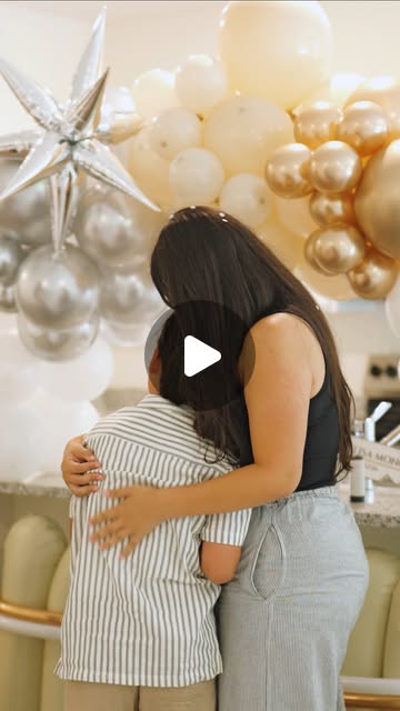 Mother hugging her son in front of gold balloons